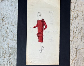 May include: A black and white fashion illustration of a woman wearing a red dress with a ruffled hem. The illustration is on a piece of paper with the number "554Y" written in the top right corner.
