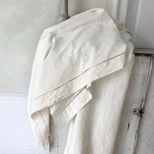 May include: A white linen tablecloth with embroidered initials "A.B." and a delicate lace trim.