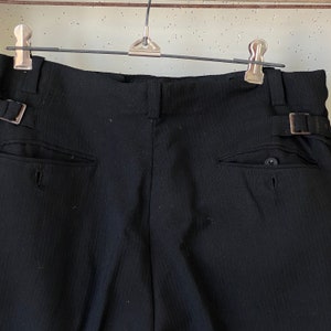 May include: Black pinstripe pants with a belt loop and a button on the back pocket.