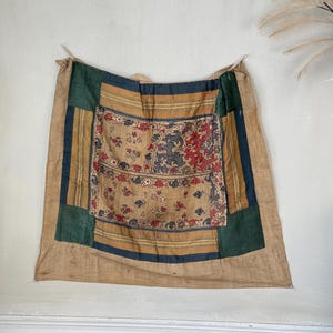 Può includere: Un arazzo vintage con un design a patchwork. Il pannello centrale presenta un motivo floreale e geometrico in tonalità di rosso, blu e verde. I pannelli circostanti sono un mix di strisce marroni, verdi e blu.