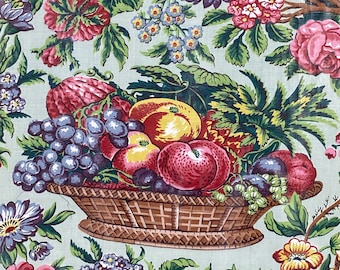 May include: A vintage floral print fabric featuring a basket overflowing with fruit, including grapes, apples, and a watermelon. The basket is surrounded by green leaves and flowers in shades of pink, blue, and yellow.