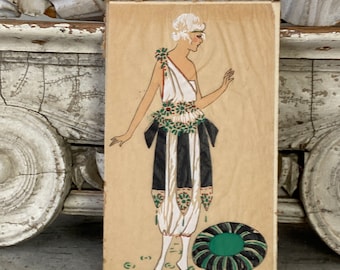 May include: A vintage illustration of a woman wearing a white dress with black and green accents. The woman has blonde hair and is standing on a light brown background. The illustration is painted on a wooden panel.