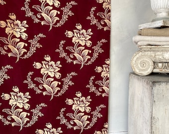 May include: A burgundy fabric with a repeating pattern of gold floral designs. The fabric has a vintage look and feel.