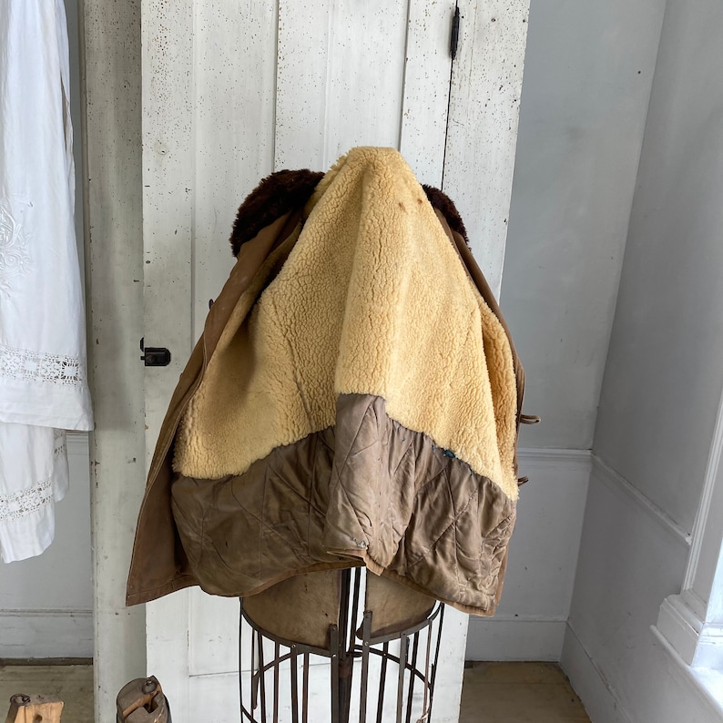 May include: A brown leather jacket with a shearling lining. The jacket is turned inside out to show the lining. The jacket is on a mannequin.