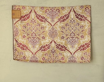 May include: A gold and red fabric with a damask pattern. The fabric has a repeating design of stylized flowers and leaves.