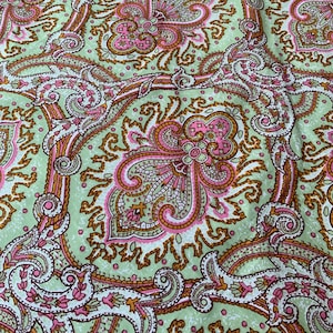 Pode incluir: Um tecido verde com um padrão paisley em tons de rosa, marrom e branco.