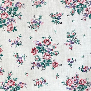 May include: White fabric with a repeating pattern of pink and purple flowers. The flowers are stylized and have a vintage look.