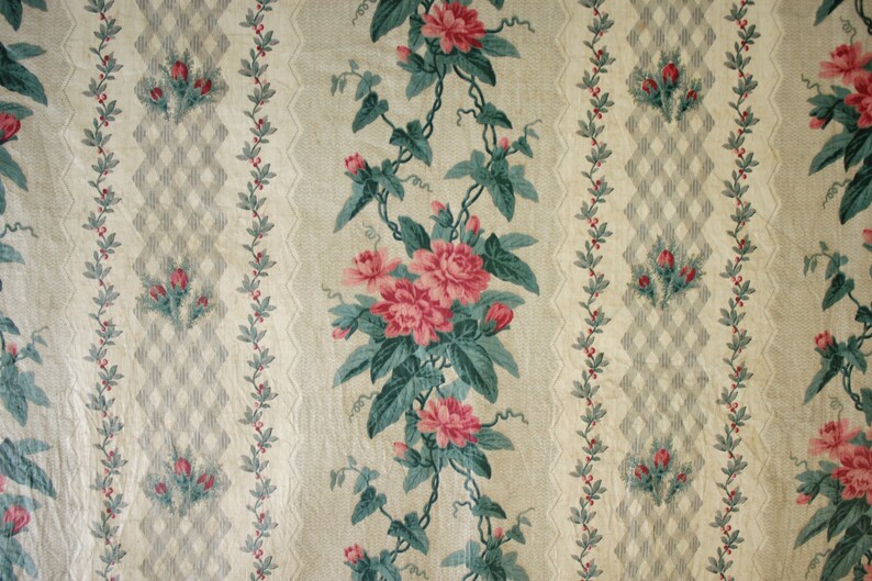 K&ouml;nnte beinhalten: Ein Vintage-Blumenstoff mit einem sich wiederholenden Muster aus rosa Rosen und gr&uuml;nen Bl&auml;ttern auf cremefarbenem Hintergrund. Der Stoff hat ein dezentes Rautenmuster in Grau und Wei&szlig;.