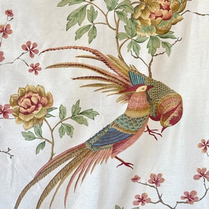 May include: A white fabric with a repeating pattern of a stylized bird with a long tail, green leaves, and pink and yellow flowers.
