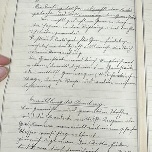 May include: A page from a vintage notebook with handwritten text in German. The text discusses the process of spinning yarn and the different types of yarn. The page is yellowed with age and has a ruled grid pattern.