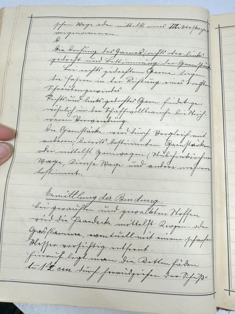 May include: A page from a vintage notebook with handwritten text in German. The text discusses the process of spinning yarn and the different types of yarn. The page is yellowed with age and has a ruled grid pattern.
