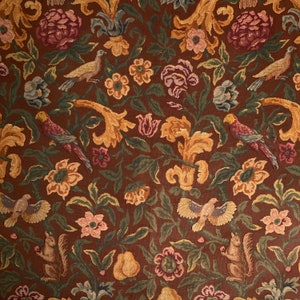 May include: A brown tapestry fabric with a repeating pattern of stylized flowers, birds, and squirrels. The fabric features a variety of colors, including green, yellow, red, and blue.