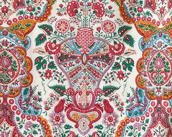 Puede incluir: Una tela blanca con un patrón paisley en tonos rojos, azules, verdes y amarillos. El patrón presenta un motivo central de un jarrón con flores.