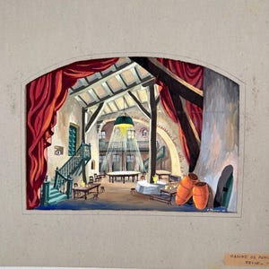 May include: An illustration of a stage set design for the "Casino de Paris Revue." The scene features a large interior with a high ceiling, wooden beams, and red curtains. A large light fixture hangs above a round table, and two orange barrels are in the foreground.