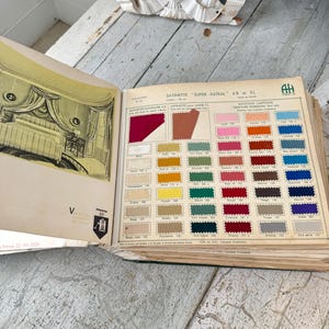 Puede incluir: Un libro de muestras de tela vintage con una variedad de colores y texturas. El libro está abierto en una página que muestra una selección de satines, incluyendo "Super Astral" y "Satine pour Laine". La página también incluye una tabla de colores de botones y telas.