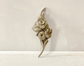 May include: A white wooden floral design with three flowers and leaves. The design is carved and has a rustic look.