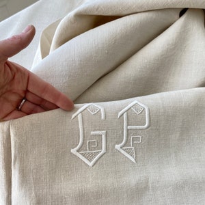 May include: White linen tablecloth with embroidered initials "GP" in a traditional script font.