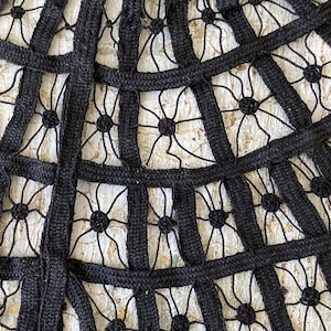 May include: Black lace fabric with a geometric pattern. The fabric is made of a thick, woven material and has a delicate, intricate design.