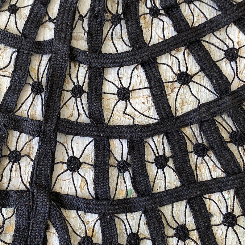 May include: Black lace fabric with a geometric pattern. The fabric is made of a thick, woven material and has a delicate, intricate design.