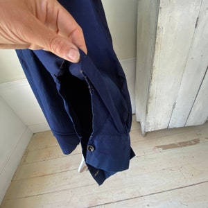 May include: A navy blue long-sleeved shirt with a button cuff. The shirt is made of a soft, lightweight fabric and has a relaxed fit.
