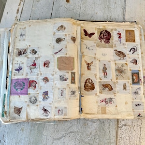May include: An antique scrapbook filled with vintage paper cutouts of animals, insects, and people. The scrapbook is open to a page with a variety of images, including a butterfly, a dog, a bird, and a fox.