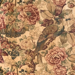 Könnte beinhalten: Ein beigefarbener Stoff mit einem floralen Muster mit rosa und braunen Blumen, grünen Blättern und einem braunen Papagei.