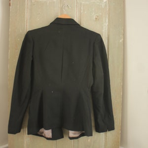 May include: A black blazer with a fitted silhouette and long sleeves. The blazer has a single button closure and a pointed collar.