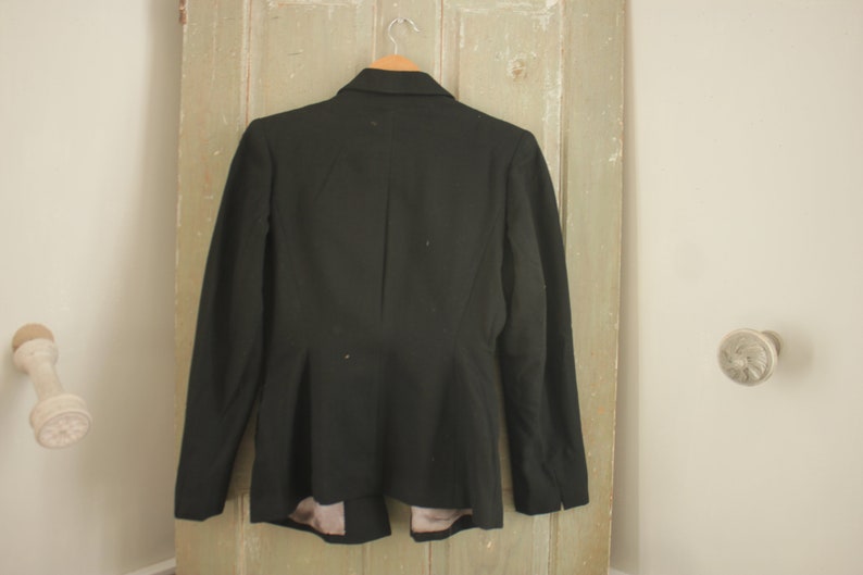 May include: A black blazer with a fitted silhouette and long sleeves. The blazer has a single button closure and a pointed collar.