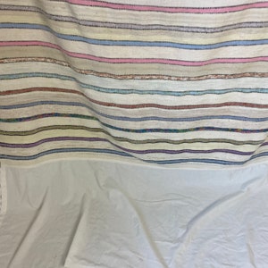 May include: A white woven throw blanket with multi-colored stripes in shades of pink, blue, purple, and brown.