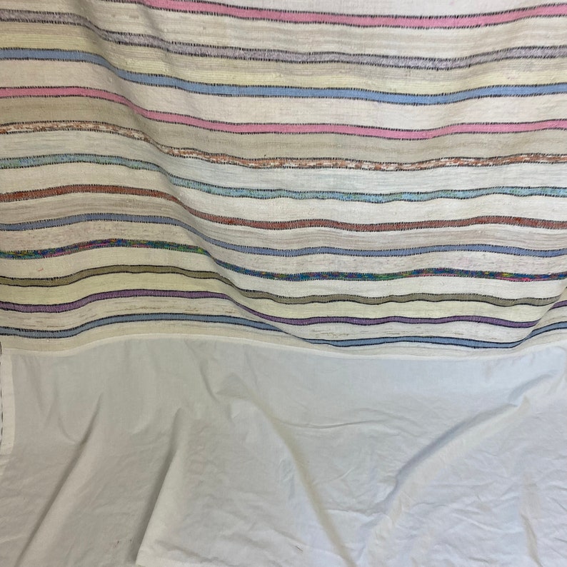 May include: A white woven throw blanket with multi-colored stripes in shades of pink, blue, purple, and brown.