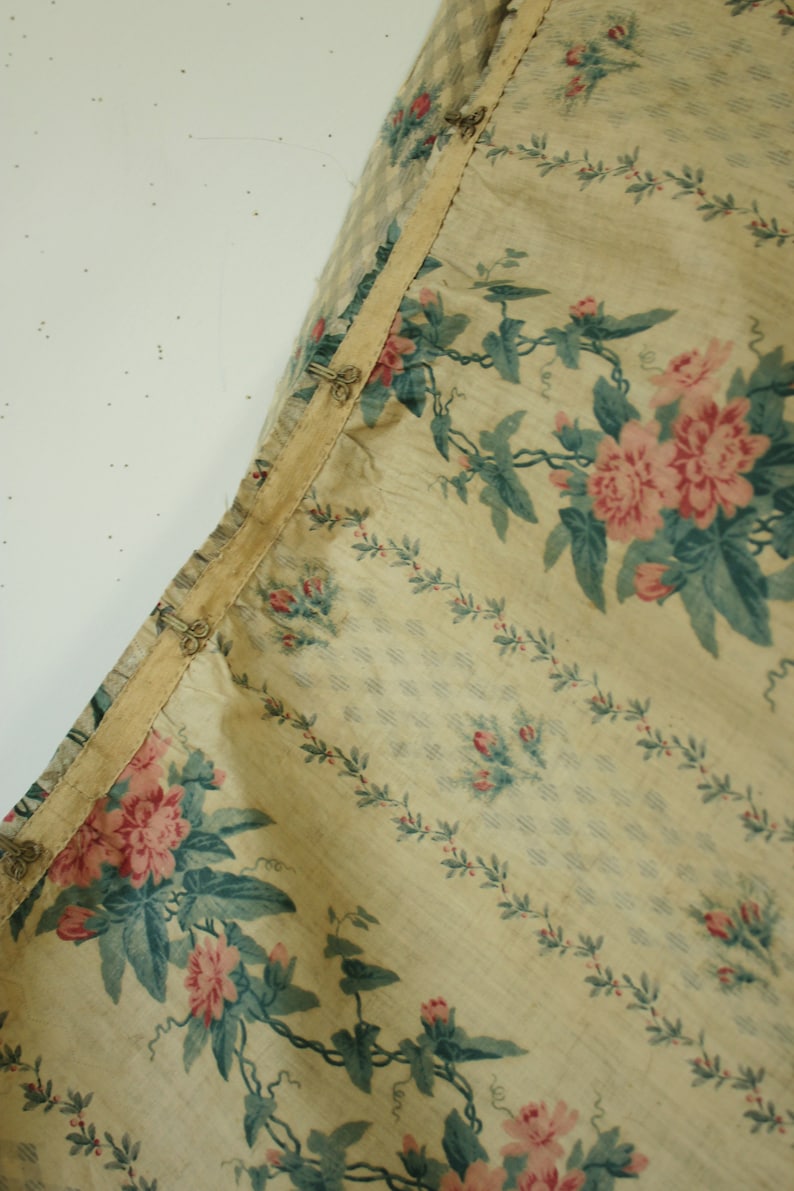 K&ouml;nnte beinhalten: Nahaufnahme eines beigefarbenen Stoffes mit Blumenmuster. Der Stoff zeigt rosa Rosen mit gr&uuml;nen Bl&auml;ttern und Ranken. Der Stoff hat einen hellbeigen Hintergrund mit einem dezenten Karomuster.