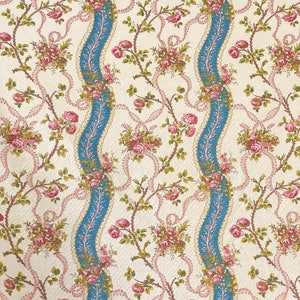 May include: A white fabric with a repeating pattern of pink and blue floral bouquets, vines, and wavy ribbons. The background is a light cream colour.