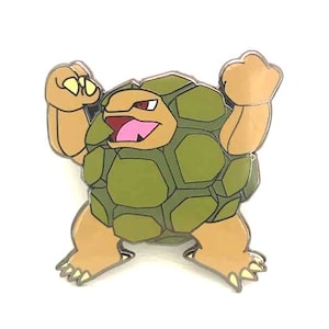 May include: A pin featuring a cartoon character with a green, segmented body and tan limbs. The character has a wide open mouth with a pink tongue and red eyes. The pin is set against a white background.