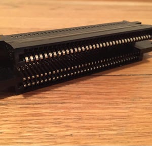 May include: A black plastic connector with two rows of gold-colored pins. The connector is designed for electronic devices.