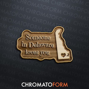 May include: Wooden sign featuring the state of Delaware with the text "Someone in Delaware loves you." The sign has a heart cutout and is made of light and dark wood.