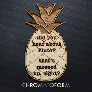 May include: Wooden pineapple-shaped sign with the text "did you hear about Pluto? that's messed up, right?" in a playful font. The sign has a natural wood grain finish and a diamond pattern.