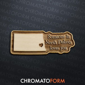 May include: Wooden sign featuring the outline of North Dakota with a heart cutout. The sign reads "Someone in North Dakota loves you" in a decorative font. The sign is made of light-colored wood with a darker wood border.