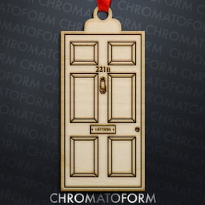 May include: Wooden ornament shaped like a door, featuring the address "221B" above the door knocker. The word "LETTERS" is visible below the knocker. A red ribbon is attached for hanging. The ornament is made of light-colored wood.