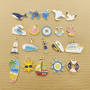 May include: A collection of twenty nautical-themed metal charms featuring colorful enamel designs including a whale, sea turtle, seashell, stingray, seagull, ocean wave, compass, anchor, coral, lighthouse, submarine, telescope, captain hat, ship, surfboard, sun, sailboat, ship wheel, and life preserver.