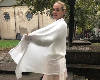 May include: A white shawl draped over a person wearing a pink tulle skirt and white heels. The person is standing on a brick staircase.