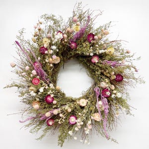 May include: A dried flower wreath with pink, white, and yellow flowers. The wreath is made of twigs and branches.