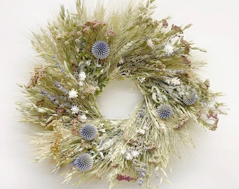 May include: A dried floral wreath with a variety of dried grasses, flowers, and seed pods in shades of beige, white, and light blue. The wreath is circular and has a diameter of approximately 12 inches.