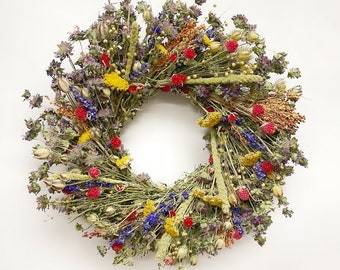 May include: A circular wreath composed of dried flowers and foliage. The wreath features a variety of colors, including red, yellow, blue, and green. The arrangement is dense and full, creating a natural and rustic aesthetic.