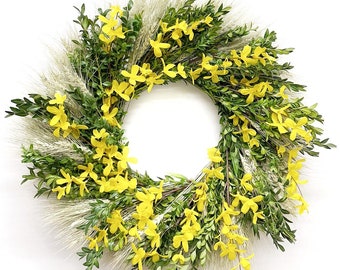 Könnte beinhalten: Ein gelber Blumenkranz mit grünen Blättern und Weizenähren. Der Kranz ist aus künstlichen Blumen gefertigt und eignet sich perfekt für die Dekoration im Frühling oder Sommer.
