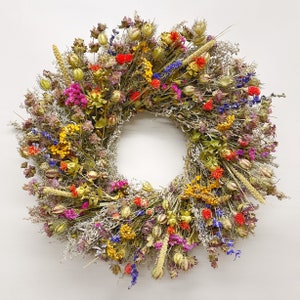 May include: A dried flower wreath featuring a mix of purple, blue, yellow, orange, and red flowers. The wreath is crafted from dried flowers and grasses, adding a touch of natural beauty to any home.