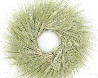 May include: A green wheat wreath with a natural, rustic look. The wreath is made of dried wheat stalks and is perfect for adding a touch of farmhouse style to your home decor.