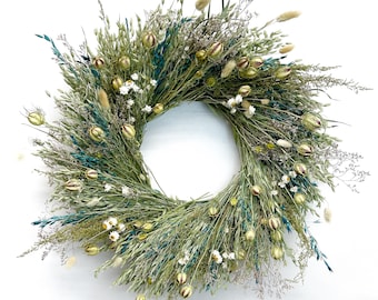 Pode incluir: Uma coroa de flores secas verde e azul com flores brancas e vagens de sementes marrons.