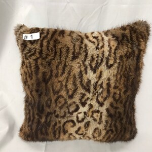 May include: A brown and white faux fur throw pillow with a leopard print pattern. The pillow has a tag that says "#1" on it.
