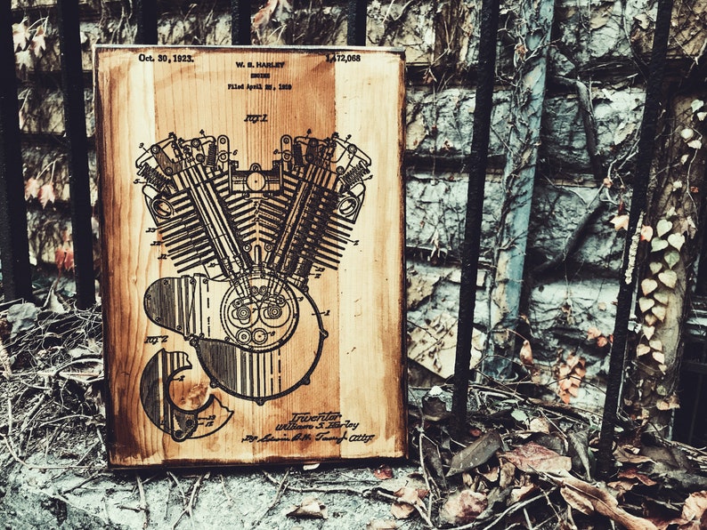 Puede incluir: Una placa de madera con un dibujo en blanco y negro de un motor Harley Davidson patentado. El n&uacute;mero de patente es 1.412.068 y la fecha es el 30 de octubre de 1923. El texto "W. S. Harley, Inventor" est&aacute; en la parte inferior de la placa.