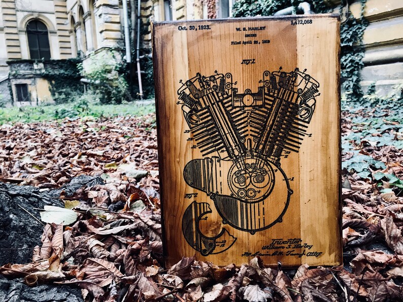 Puede incluir: Una placa de madera con un dibujo en blanco y negro de una patente de motor Harley Davidson. El n&uacute;mero de patente es 1,472,068 y la fecha es el 30 de octubre de 1923. El inventor es William S. Harley.